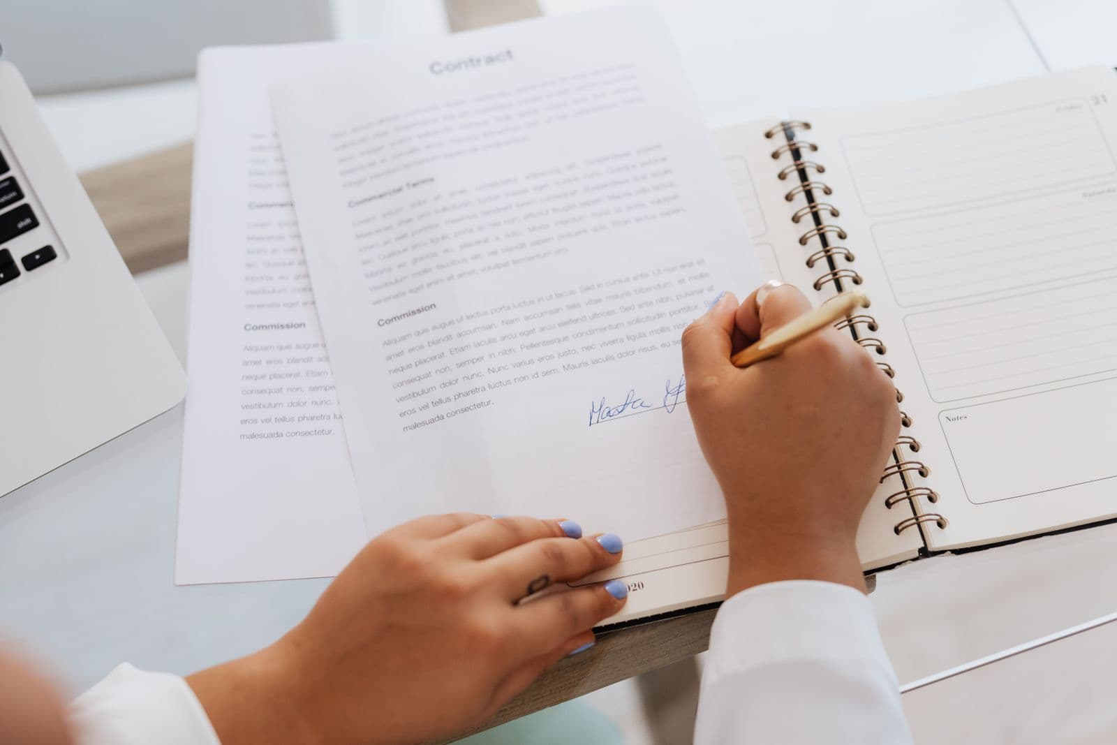 A contract being signed with a pen at a desk