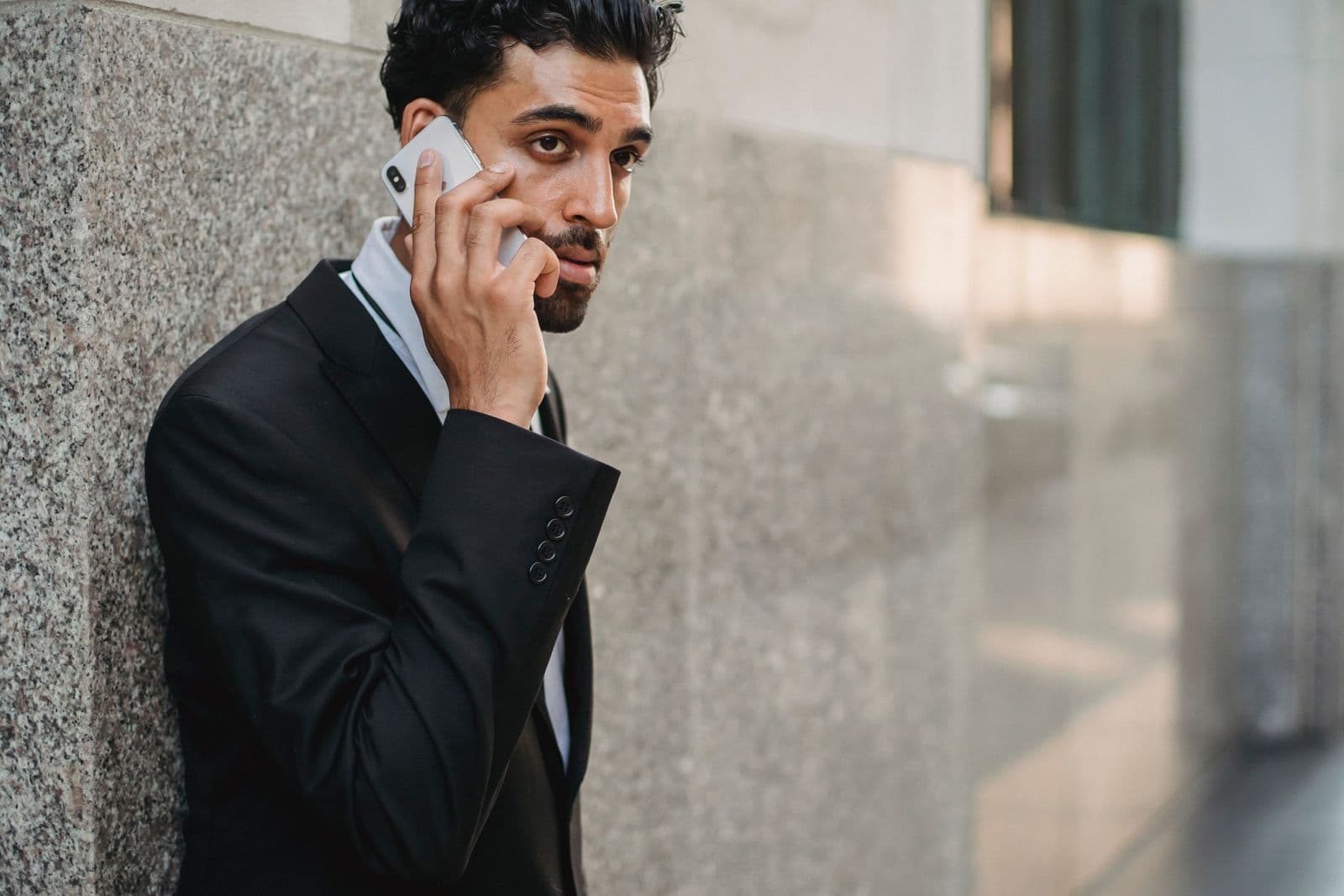 A man in a suit taking a phone call outside an office building