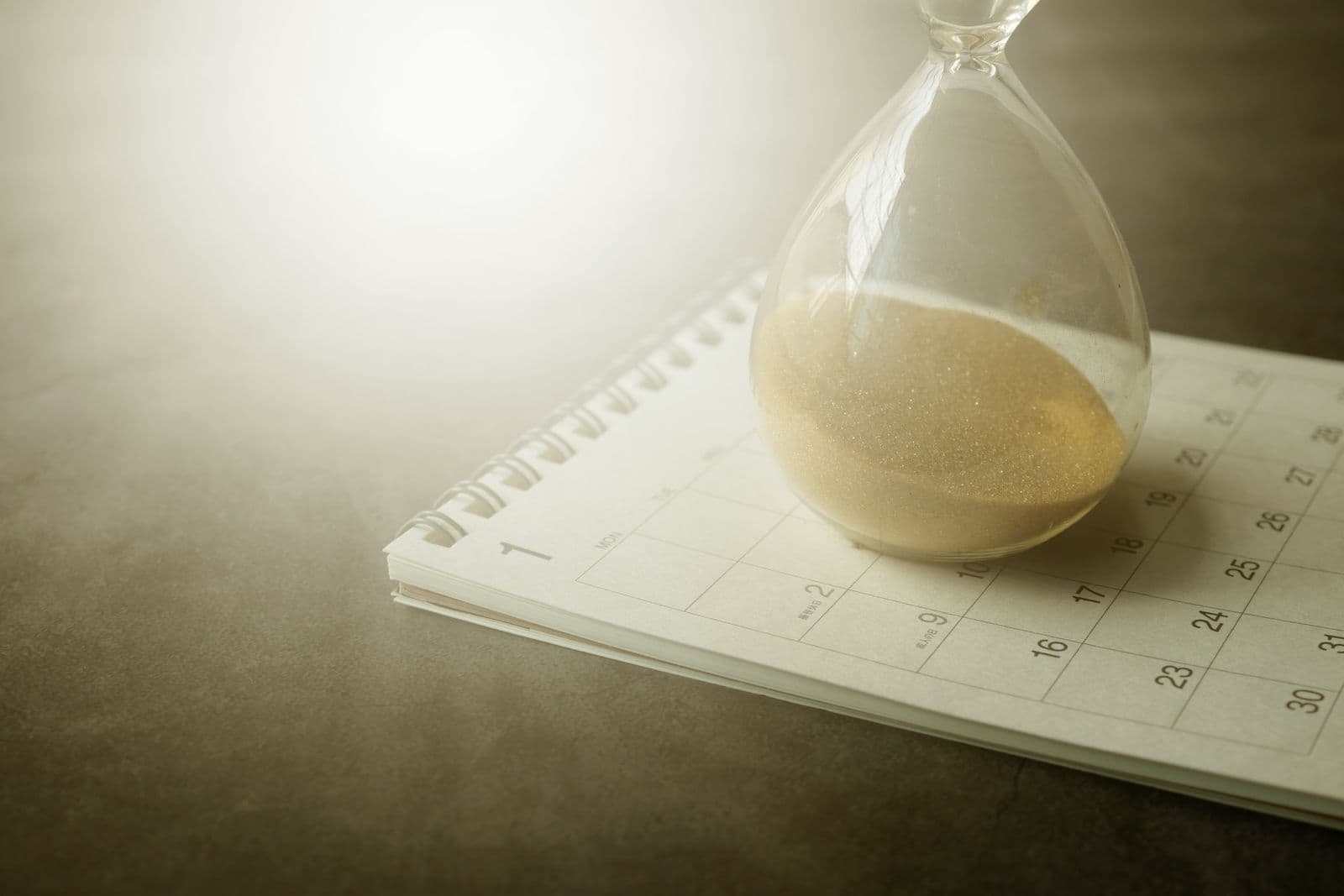 An hourglass running down on top of a monthly calendar